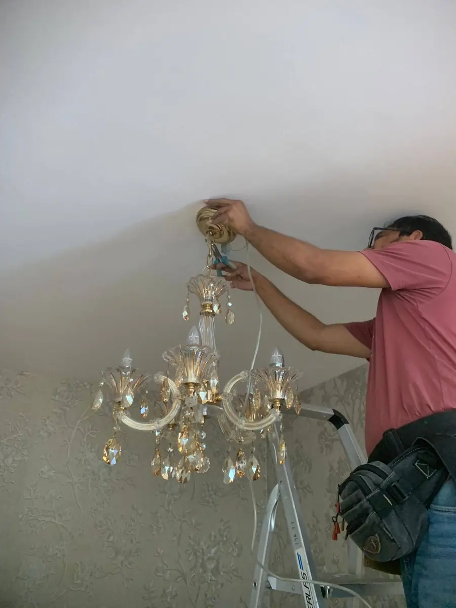 SG Electrician electrician installing a crystal chandelier in a Singapore home